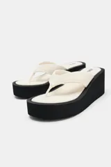 Sandalias de plataforma color negro, con diseño de tira de dedo y suela alta tipo cuña.