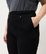 Pantalón de jean corte flare color negro, con cintura estructurada, bolsillos funcionales y recortes frontales con remaches brillantes.