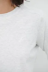 Remera de manga larga en color gris melange, con cuello redondo y costuras reforzadas en los hombros y mangas.