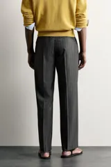 Pantalón de vestir gris con diseño de rayas sutiles, de corte relaxed fit, con pinzas delanteras y trabillas para cinturón.