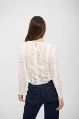 Top de encaje blanco con diseño de rayas verticales, manga larga y cuello redondo.