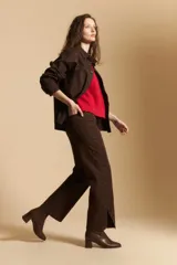 Pantalón de corte recto y tiro medio, color marrón, con detalle de tachas metálicas a lo largo de las costuras laterales y tajos en el ruedo.