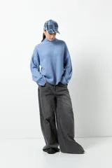 Polera gris de tejido tramado, cuello alto y mangas holgadas.