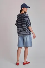 Remera oversize a rayas horizontales en tonos bordó y blanco, con cuello redondo verde oscuro y un pequeño parche bordado en forma de corazón en el pecho.