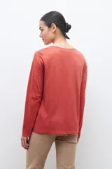 Remera blanca de manga larga con bordado floral azul en el escote.