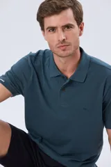 Remera polo de piqué de algodón color azul, de manga corta, con cuello camisero, cierre frontal de dos botones y pequeño logo bordado en el pecho.