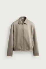 Cazadora regular fit de hombre confeccionada en tejido efecto ante, de color gris, con cuello solapa, mangas largas con puño abotonado, bolsillos de vivo en la cadera, bajo elástico y cierre frontal con cremallera.