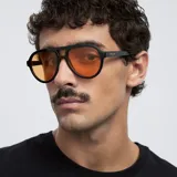 Lentes de sol de aviador con montura negra y lentes naranjas. Fabricados con materiales bio-based G850 y patillas de propionato de celulosa. Cuentan con protección UV400 y lentes TAC polarizadas con recubrimiento antiscratch y superhydrophobic.
