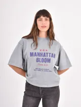 Remera de corte holgado y diseño oversize, color azul piedra con efecto lavado. Presenta un estampado gráfico frontal con tipografía y un pequeño dibujo de una rosa.