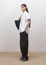 Camisa de algodón de diseño recto, cuello camisero, manga tres cuartos y cierre delantero de botones ocultos con tapeta.