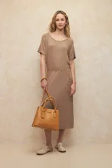 Vestido largo color beige de punto elastizado, con cuello bote y mangas cortas. Incluye cinturón dorado de cadena.