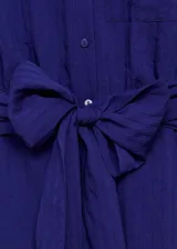 Vestido midi de corte evasé y diseño sin mangas, confeccionado en tejido texturizado color azul. Presenta cuello camisero, cierre frontal con botones, bolsillo de parche en el pecho y un lazo ajustable en la cintura.