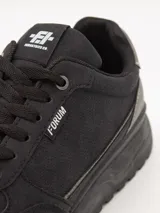 Zapatillas urbanas negras con suela gruesa y cordones.