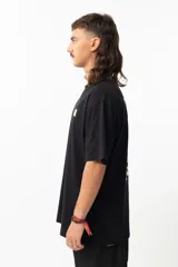 Remera negra de algodón con estampa en la espalda de una ilustración de Adrian Willard que representa una mujer con una rosa en el pelo y un cráneo fumando, sobre un fondo con damero y texto en japonés.