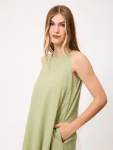 Vestido midi sin mangas de corte recto y holgado, color beige, con cuello redondo y bolsillos laterales.