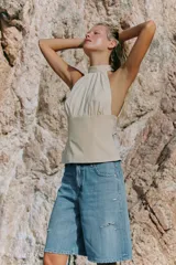Top halter combinado con cuello subido ajustable mediante botones y hombros descubiertos, de diseño bicolor en tonos beige y blanco con sutiles rayas verticales.