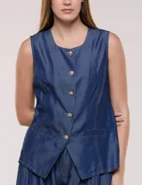 Chaleco de lyocell color azul, con escote redondo, sin mangas, cierre frontal con botones metálicos y bolsillos en la cintura.