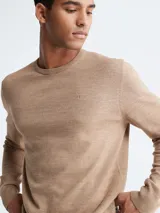 Sweater de punto color beige melange, de manga larga y cuello redondo, con un pequeño monograma bordado en el pecho.