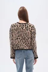 Cardigan de tejido de punto, corto, con estampado animal print en tonos beige y negro. Presenta cuello redondo y ribetes negros en el borde frontal, puños y ruedo.