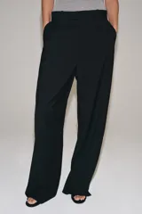 Pantalón de lana negro de tiro medio con trabillas en la cintura, bolsillos laterales ocultos y pierna ancha.