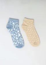 Pack de dos pares de medias de tobillo con diseños estampados. Un par es celeste con estampado floral blanco, y el otro es beige con lunares blancos.