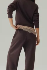 Pantalón de corte holgado en punto pesado con leve brillo, color marrón, con elástico revestido en la cintura, bolsillos al bies y piernas rectas con pliegues cosidos.