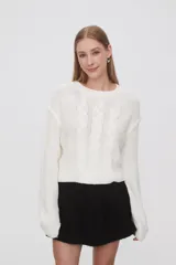 Sweater de punto color celeste, con diseño de trenzas frontales, cuello redondo y corte holgado.