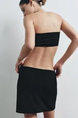 Falda mini de tiro bajo, confeccionada en tejido liso de color negro, con diseño minimalista y cintura elástica.