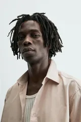 Camisa slim fit color beige, confeccionada en tejido de algodón, con cuello italiano y manga larga con puño de botón. Cierre frontal de botonadura.