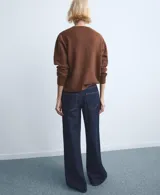 Jeans de denim azul oscuro con diseño de tiro medio y corte ancho en las piernas, con bolsillos delanteros y traseros.