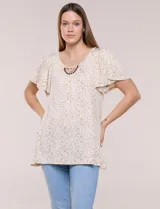 Blusa de tejido estampado con diseño de mandalas en tonos beige y blanco, escote redondo amplio con detalle de aplique bordado artesanal y cuentas de madera, mangas cortas estilo mariposa y ruedo asimétrico.