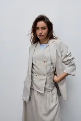 Blazer beige de corte recto, con solapa clásica, bolsillos frontales con solapa y cierre de un botón.