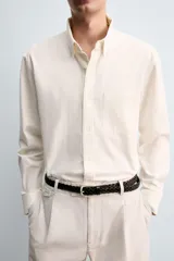 Camisa de corte relajado confeccionada en tejido de algodón, con cuello solapa, manga larga con puños abotonados, bolsillo frontal en el pecho y cierre de botonadura.