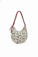 Cartera de hombro con diseño de media luna, confeccionada en tela con estampado animal print en tonos blanco y negro. Cuenta con una correa larga de cuerda trenzada en color bordó con detalle de nudo ajustable.