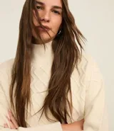 Suéter de manga larga confeccionado en tricot, con cuello alto y diseño de rombos bordados en relieve. Presenta puños y cintura ajustados en tejido acanalado.