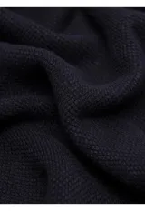 Sweater de punto color azul marino, con cuello alto y cierre frontal parcial de botones. Presenta puños y ruedo acanalados.