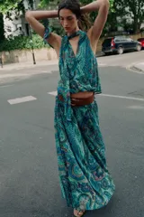 Top sin mangas de cuello alto con lazo ajustable, escote en V y diseño cruzado en el delantero. Presenta un estampado paisley en tonos verdes, azules y rosados, con bajo elástico y forro interior.
