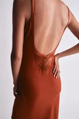 Vestido largo de corte recto y color teja, con escote en V y tirantes finos. Presenta detalles de acabados en tejido satinado combinado a tono en el escote y cierre lateral con cremallera oculta.
