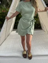 Vestido corto blanco de lino con corte evasé, mangas cortas con volados y cinto del mismo material.