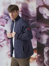 Campera azul marino con cierre frontal, cuello alto y bolsillos laterales con cierre. Tiene un parche rojo con cierre en la manga izquierda y un diseño acolchado en la parte delantera.