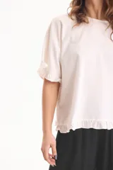Blusa de lino color crudo, de manga corta con detalles de volados en las mangas y en el ruedo.