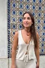 Chaleco de tejido artesanal en color amarillo, con escote en V y cierre frontal mediante lazos anudados. Presenta un diseño sin mangas y corte recto.