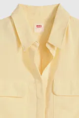 Camisa de lino color amarillo pastel, con bolsillos frontales con solapa, mangas largas remangadas y cierre frontal con botones.