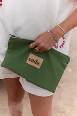 Neceser tipo sobre color verde militar con cierre superior y parche de cuero con el logo de la marca Cada.