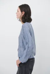 Chaqueta ligera de manga larga en color azul, con escote en V y cierre frontal mediante dos lazos ajustables. Presenta un diseño fluido con textura sutil y corte recto.