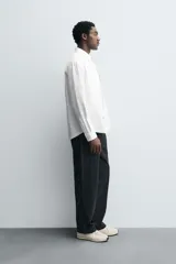 Pantalón de corte relaxed fit confeccionado en mezcla de algodón y modal. Presenta cintura con pliegues frontales, bolsillos laterales y bolsillos traseros con solapa. Cierre frontal con cremallera y botón.