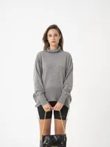 Sweater gris de tejido fino con cuello alto, silueta amplia y hombro caído.