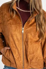 Campera tipo bomber de gamuza sintética color camel, con cierre frontal, cuello alto y diseño oversize.