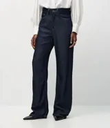Pantalón de corte recto y cintura alta, confeccionado en denim crudo (raw denim) de color azul oscuro. Presenta cierre frontal con botón y cremallera, trabillas para cinturón y bolsillos funcionales en frente y espalda.