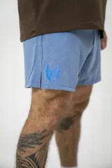 Short deportivo celeste con estampado de logo en la pierna izquierda y aberturas laterales.
